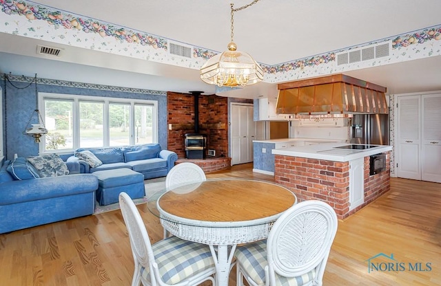 dining room featuring a wood stove, light wood-style flooring, and visible vents