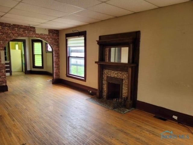 unfurnished living room with hardwood / wood-style floors and a drop ceiling