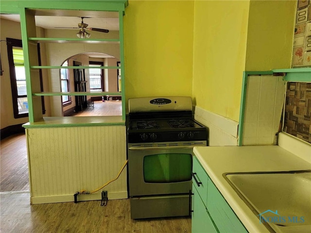 kitchen with stainless steel range with gas cooktop, sink, ceiling fan, and light wood-type flooring