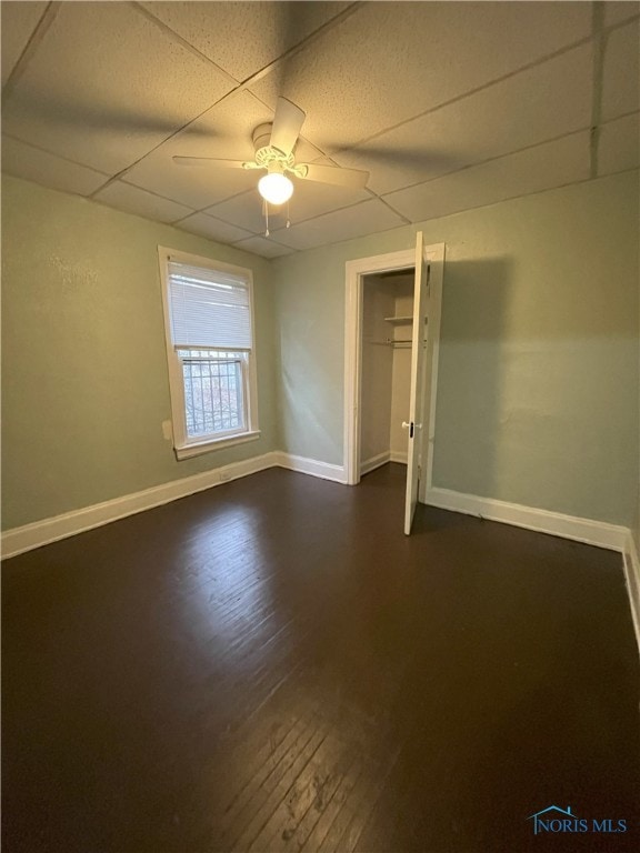 unfurnished room with ceiling fan, baseboards, and dark wood-style flooring