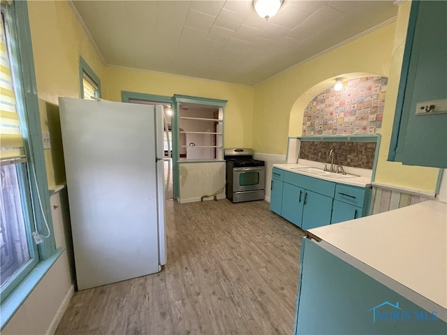 kitchen featuring stainless steel range, freestanding refrigerator, light countertops, light wood-type flooring, and a sink