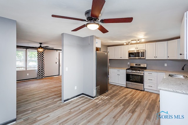 kitchen featuring ceiling fan, stainless steel appliances, sink, and white cabinetry