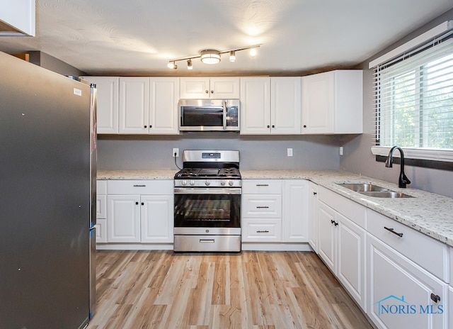 kitchen with white cabinets, light hardwood / wood-style floors, appliances with stainless steel finishes, and sink