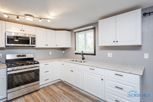 kitchen featuring appliances with stainless steel finishes, light wood-type flooring, sink, and white cabinetry