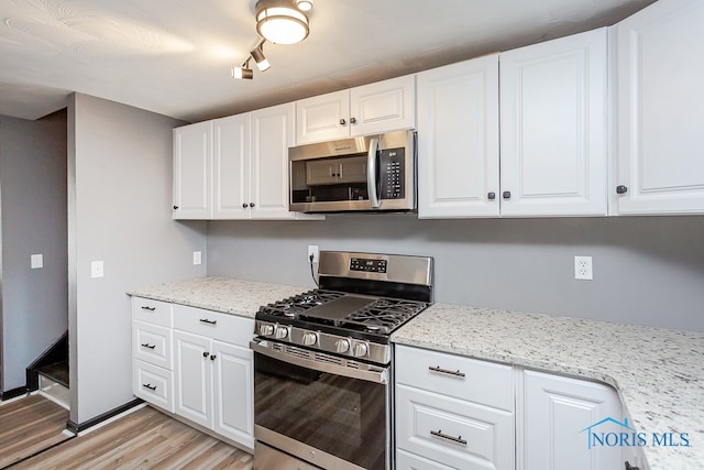 kitchen with light stone countertops, stainless steel appliances, light hardwood / wood-style floors, and white cabinetry