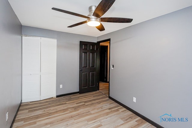 unfurnished bedroom featuring light wood-type flooring, ceiling fan, and a closet