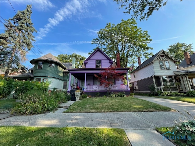 victorian house with a front lawn and a porch