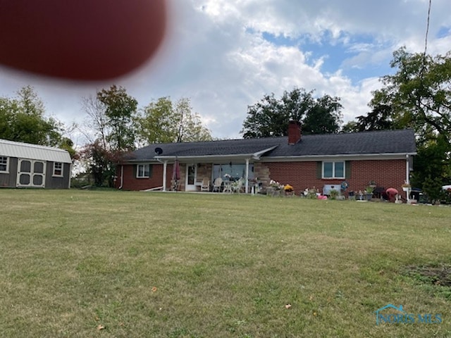 rear view of property featuring a yard and a storage shed