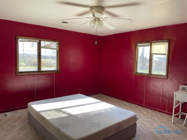 unfurnished bedroom with ceiling fan, multiple windows, and light carpet