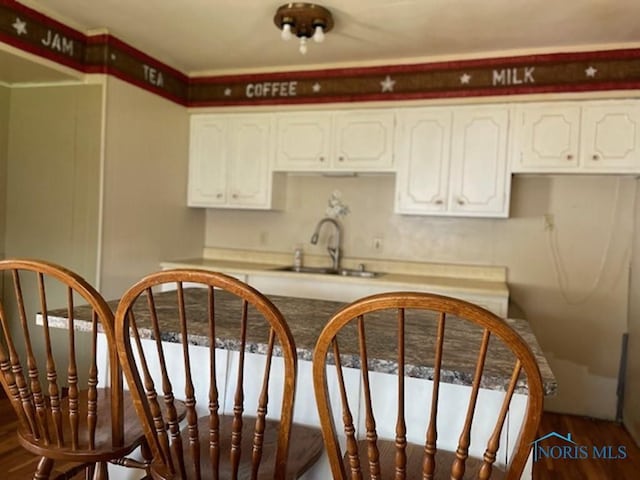 kitchen with white cabinetry, sink, and hardwood / wood-style flooring