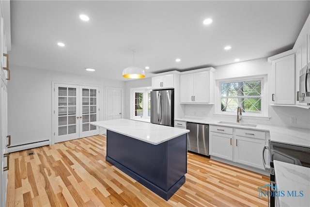 kitchen with appliances with stainless steel finishes, plenty of natural light, sink, and white cabinetry