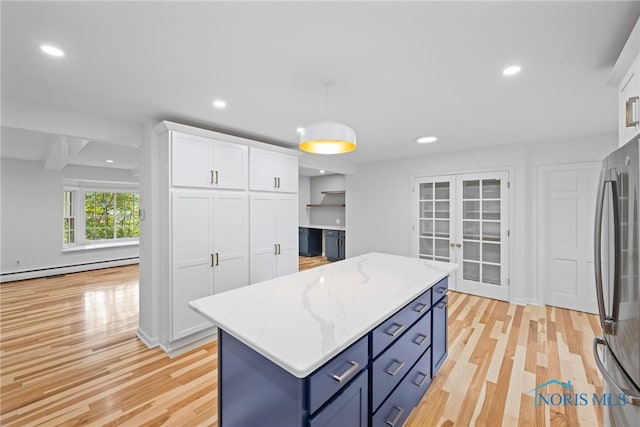 kitchen with hanging light fixtures, stainless steel refrigerator, light hardwood / wood-style flooring, and white cabinets