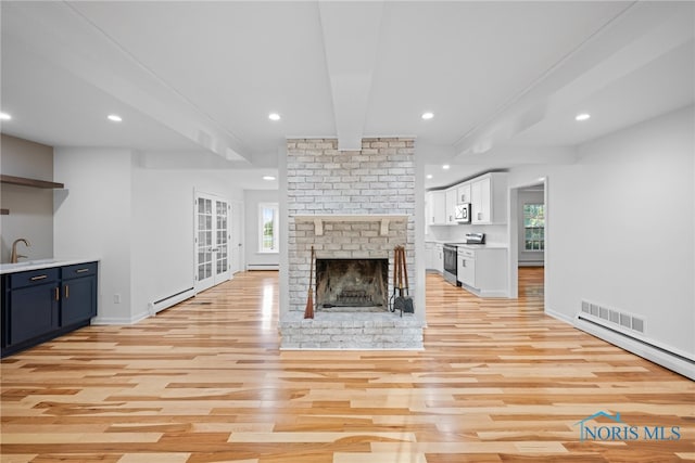 unfurnished living room with a fireplace, baseboard heating, and light hardwood / wood-style flooring