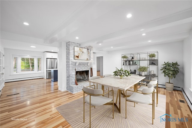 dining space featuring a fireplace, beam ceiling, light hardwood / wood-style flooring, and a baseboard radiator