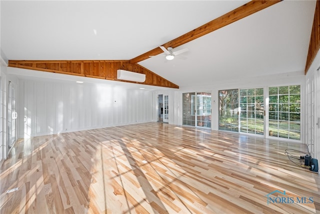 unfurnished living room featuring ceiling fan, a wall mounted AC, wooden walls, light hardwood / wood-style flooring, and lofted ceiling with beams