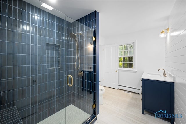 bathroom featuring walk in shower, vanity, toilet, and a baseboard heating unit