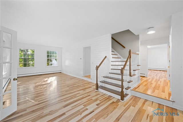 unfurnished living room featuring brick wall, light hardwood / wood-style flooring, and baseboard heating