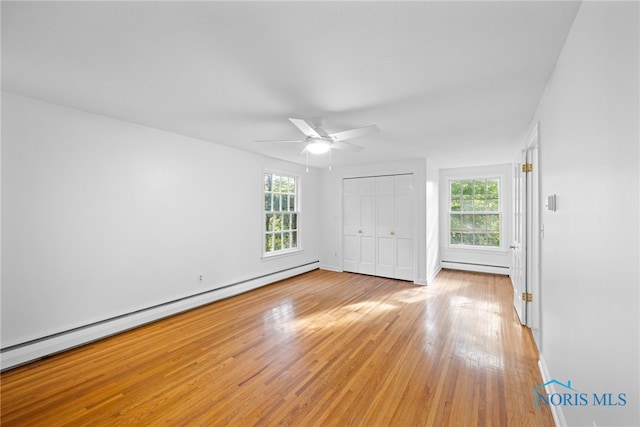 unfurnished bedroom featuring light hardwood / wood-style flooring, a baseboard heating unit, a closet, and ceiling fan