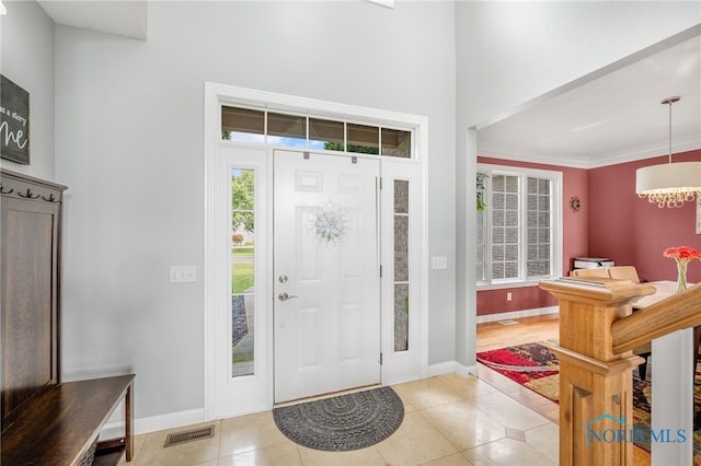 foyer entrance featuring light tile patterned flooring and crown molding