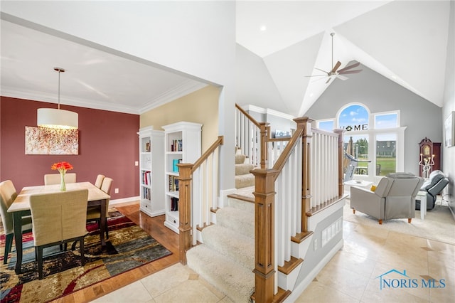 dining area featuring ceiling fan, light wood-type flooring, crown molding, and high vaulted ceiling