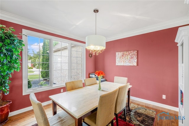 dining room featuring an inviting chandelier, light wood-type flooring, and ornamental molding