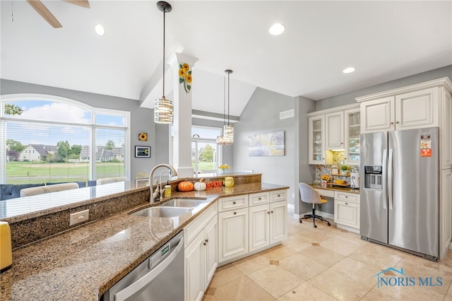 kitchen featuring dark stone countertops, vaulted ceiling, appliances with stainless steel finishes, and white cabinets