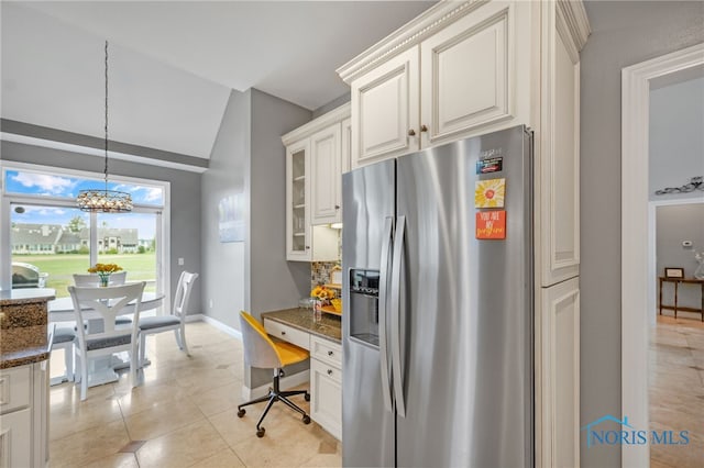 kitchen featuring built in desk, stainless steel refrigerator with ice dispenser, white cabinetry, and dark stone counters