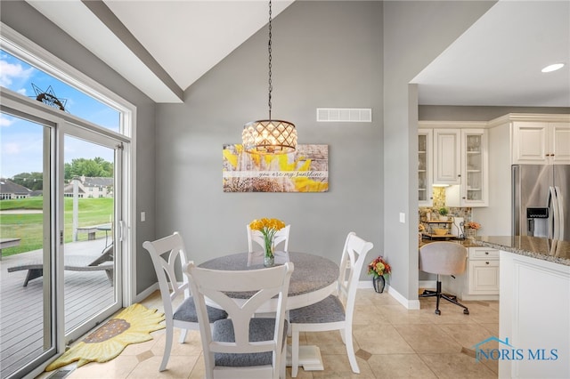 tiled dining room featuring high vaulted ceiling