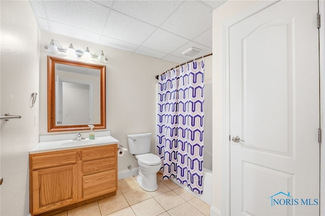 full bathroom with shower / tub combo, vanity, a drop ceiling, toilet, and tile patterned floors