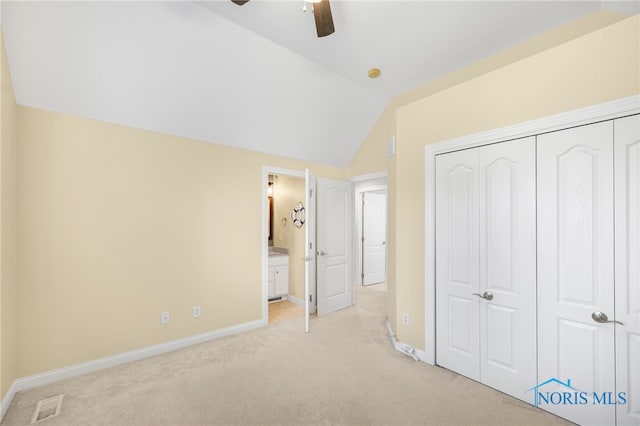 unfurnished bedroom with ceiling fan, a closet, light carpet, ensuite bath, and vaulted ceiling