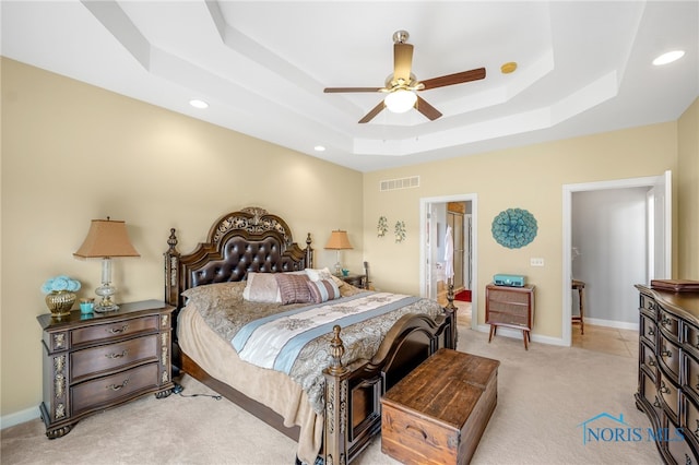 carpeted bedroom with connected bathroom, a tray ceiling, and ceiling fan