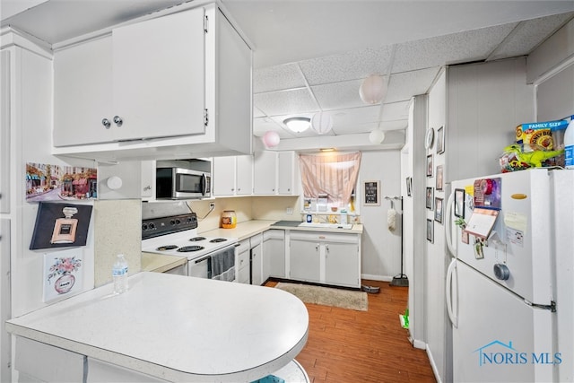 kitchen with sink, white cabinetry, a drop ceiling, light hardwood / wood-style flooring, and white appliances