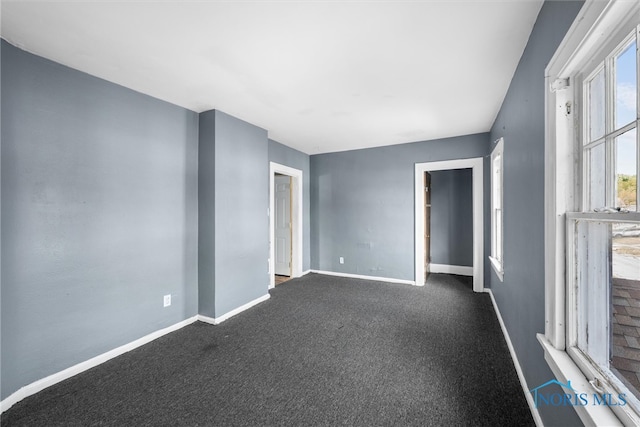 unfurnished room with dark colored carpet