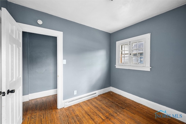 spare room with baseboard heating and dark hardwood / wood-style flooring