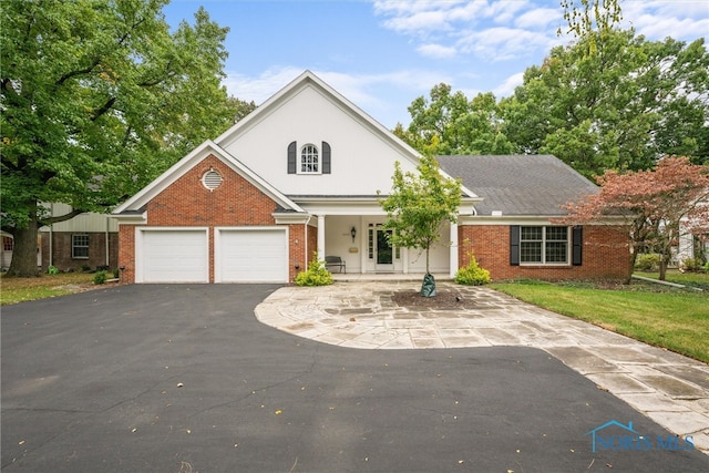 view of front of house featuring covered porch, a front yard, and a garage