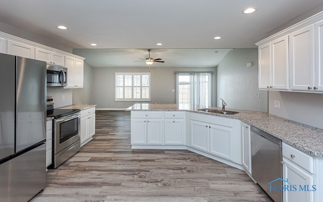 kitchen with appliances with stainless steel finishes, kitchen peninsula, and white cabinets