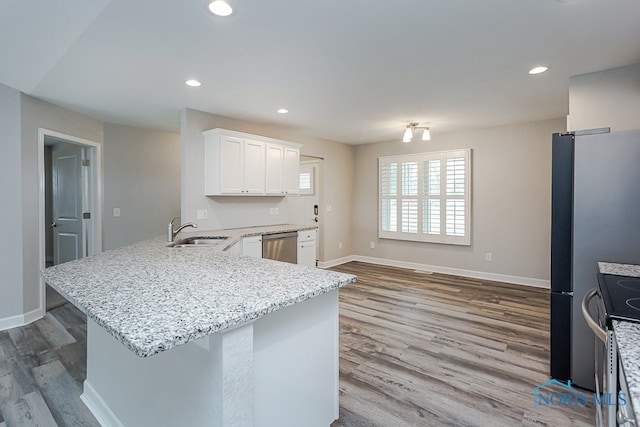 kitchen featuring sink, kitchen peninsula, white cabinetry, appliances with stainless steel finishes, and light wood-type flooring