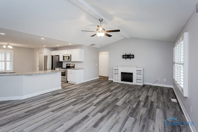 unfurnished living room with lofted ceiling with beams, ceiling fan, a fireplace, and dark wood-type flooring