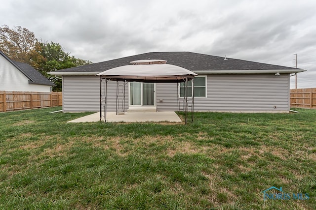 back of property with a lawn, a patio area, and a gazebo