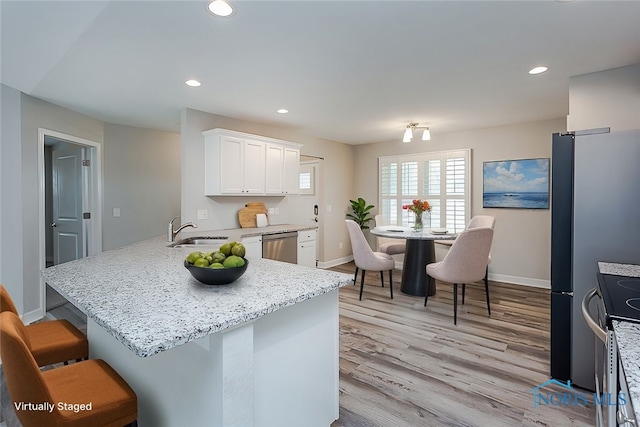 kitchen with light hardwood / wood-style floors, sink, a breakfast bar area, white cabinets, and kitchen peninsula