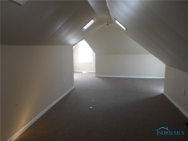 additional living space featuring vaulted ceiling and carpet flooring