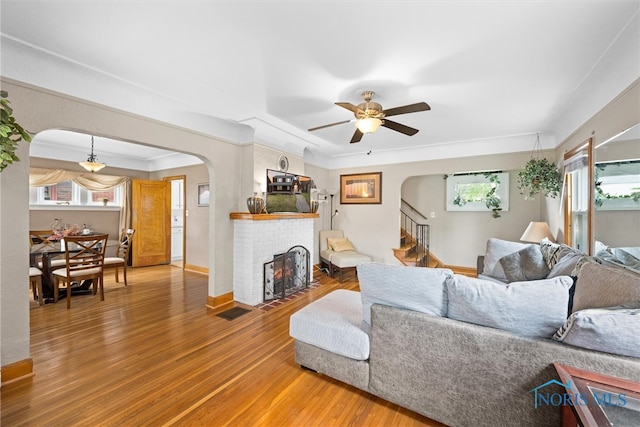 living room featuring wood-type flooring, a fireplace, ceiling fan, and a wealth of natural light