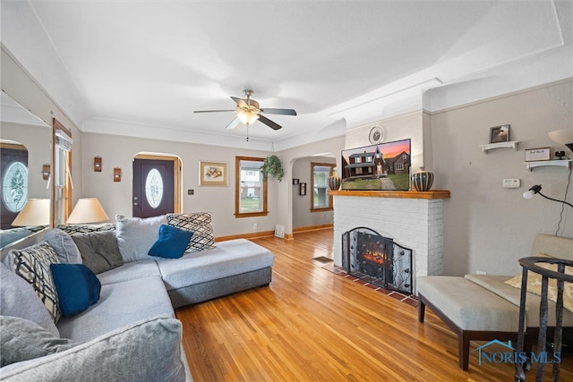 living room featuring ceiling fan, a brick fireplace, and hardwood / wood-style flooring