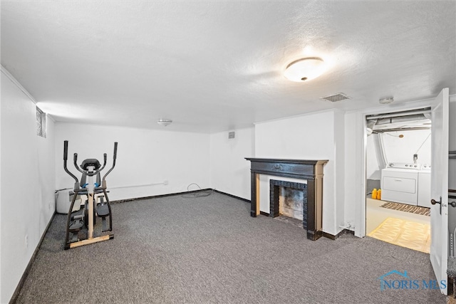 workout room featuring washing machine and clothes dryer, dark colored carpet, and a textured ceiling