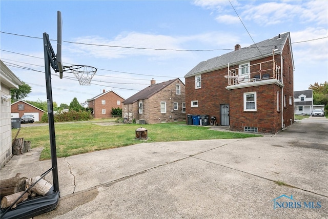 back of property featuring a balcony and a yard