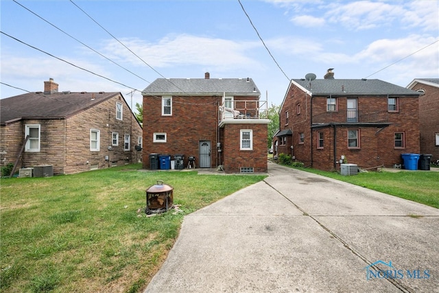 rear view of property with cooling unit and a lawn