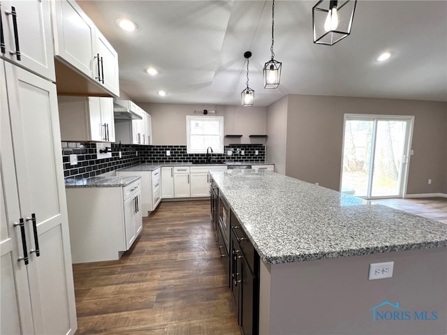 kitchen with pendant lighting, dark hardwood / wood-style flooring, a center island, and white cabinets