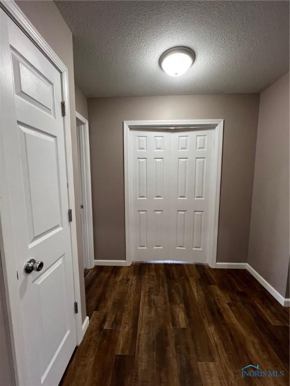 hall with dark hardwood / wood-style floors and a textured ceiling