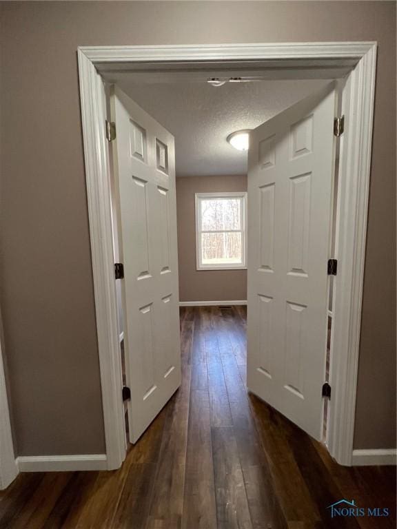 hall featuring a textured ceiling and dark hardwood / wood-style flooring