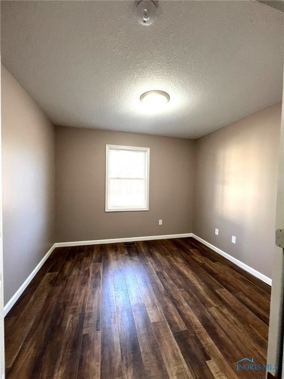 empty room with dark hardwood / wood-style flooring and a textured ceiling